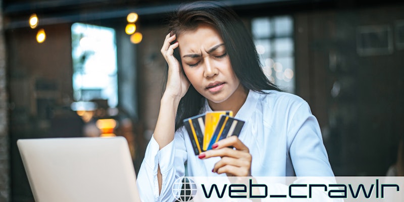 A woman looking frustrated and holding credit cards. The Daily Dot newsletter web_crawlr logo is in the bottom right corner.
