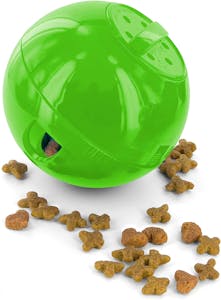 A lime green plastic PetSafe Slimcat Feeder Ball with cat food spilling out of it.