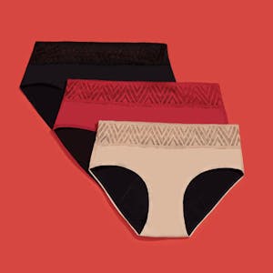 A black, red, and beige pair of Thinx underwear against a red background.