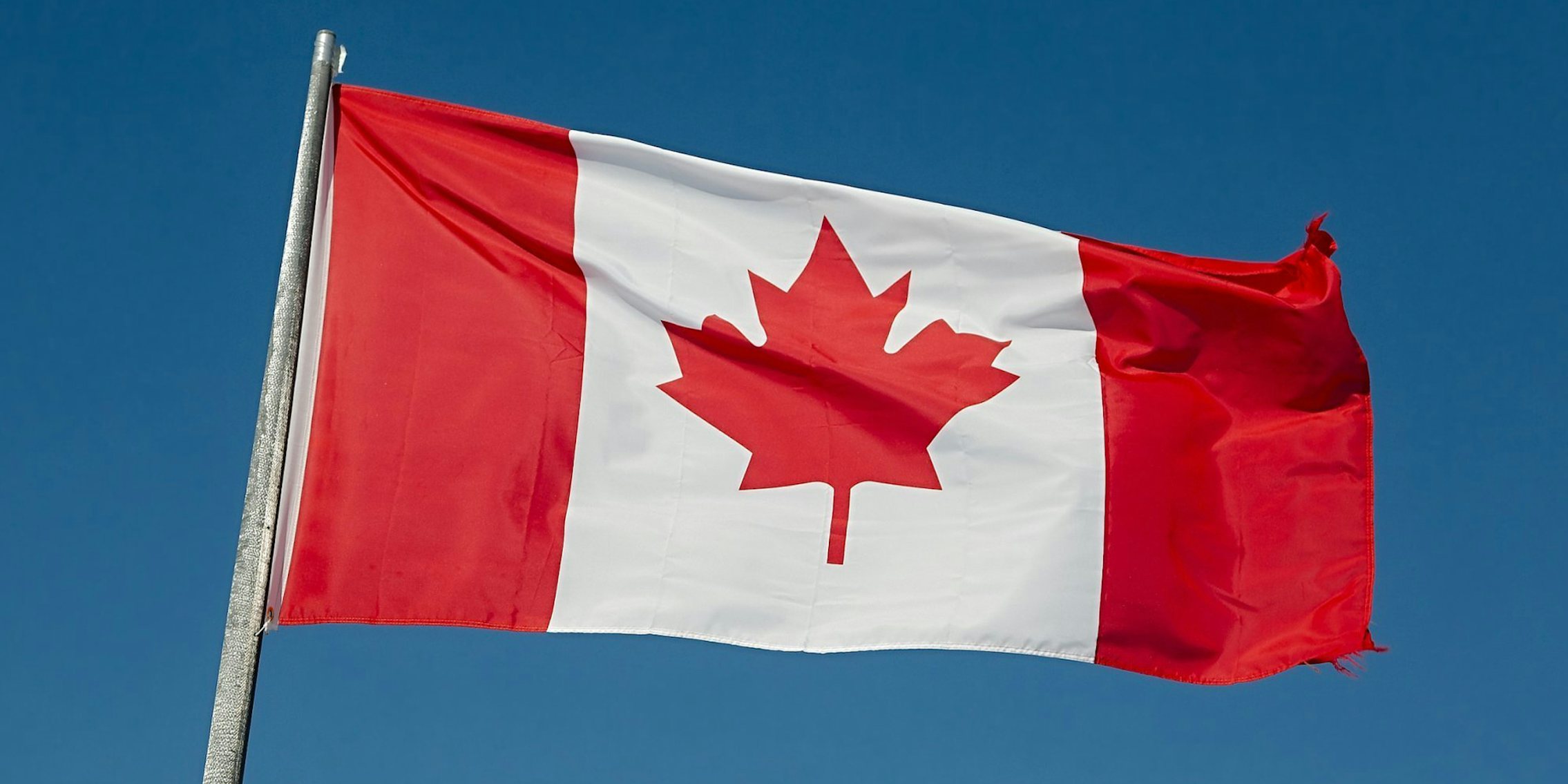 Canadian flag waving outside with blue sky