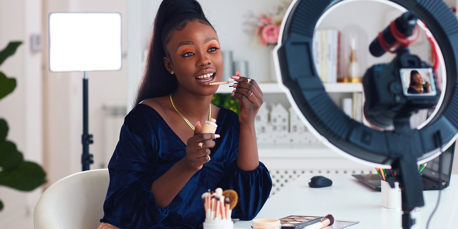 young woman of color streaming a beauty vlog from home, online content creator