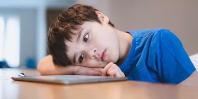 child using tablet with head on table
