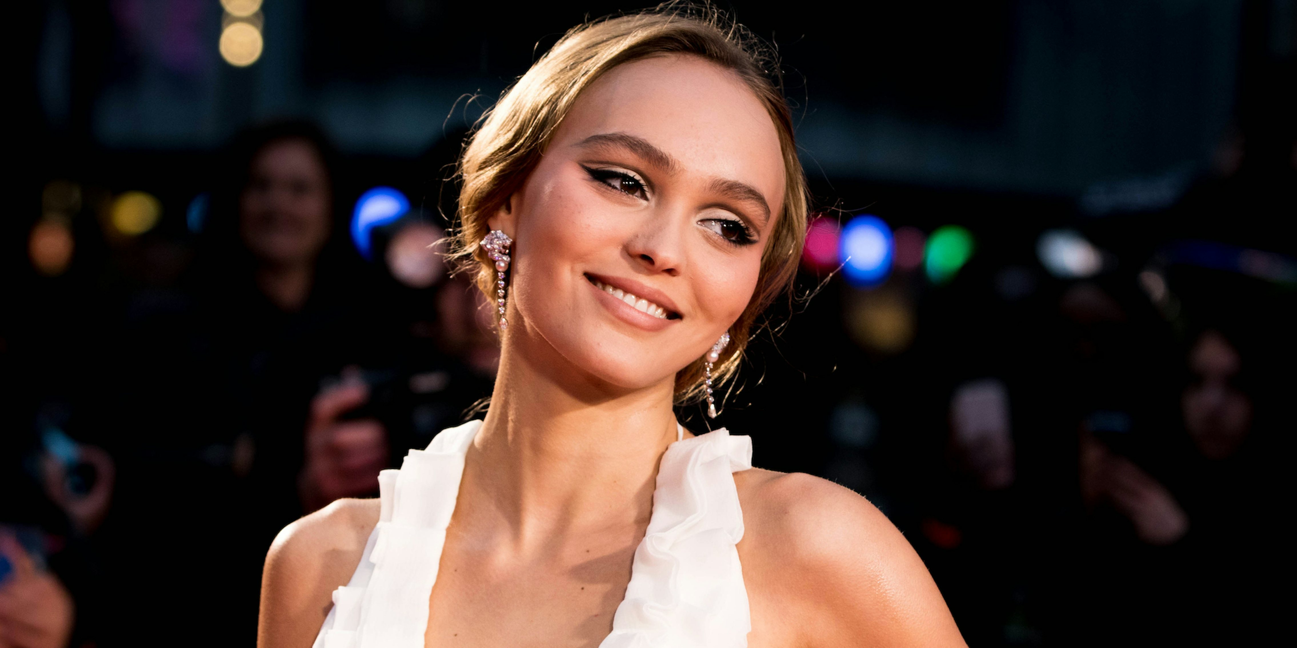 lily rose depp smiling in a white dress