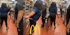 McDonald's workers holding equipment while fighting in kitchen (l) McDonald's worker grabbing equipment while fighting in kitchen with McDonald's golden arches 