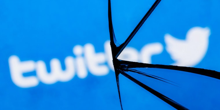 Twitter logo blurred with broken glass on blue background