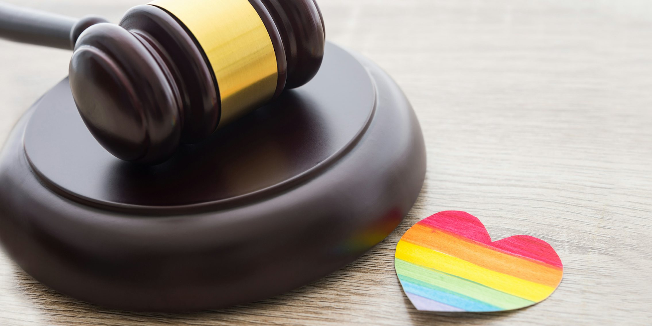 wooden gavel with rainbow heart cutout on white wooden surface