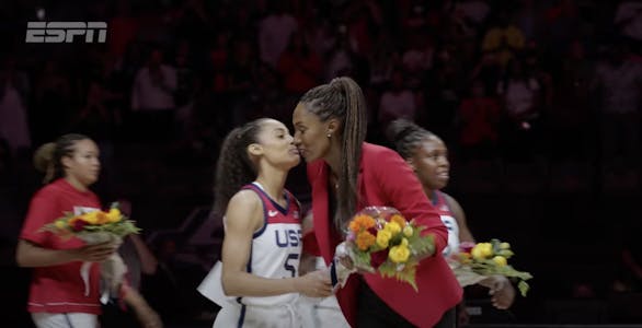 A screenshot from the trailer for the 2022 ESPN documentary "Dream On" showing a member of the 1996 U.S. Women's Olympic basketball team kissing the coach as she gives her flowers.
