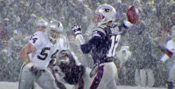A screenshot from the 2022 ESPN documentary "The Tuck Rule" showing New England Patriots quarterback Tom Brady poised to throw a football in heavy snow.