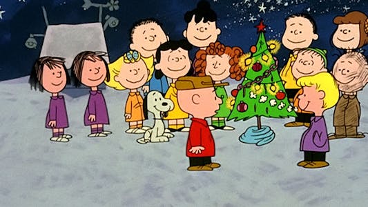 Charlie Brown and the rest of the Peanuts gang standing around a Christmas tree.