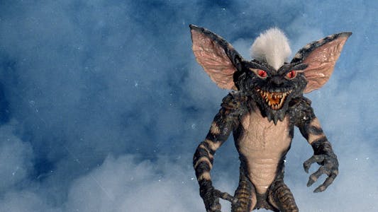 best christmas movies streaming - A gremlin with a white mohawk in front of what appears to be smoke or snow.