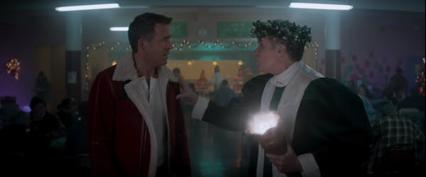 Ryan Reynolds in a winter coat with Will Ferrell dressed as the Ghost of Christmas Present.