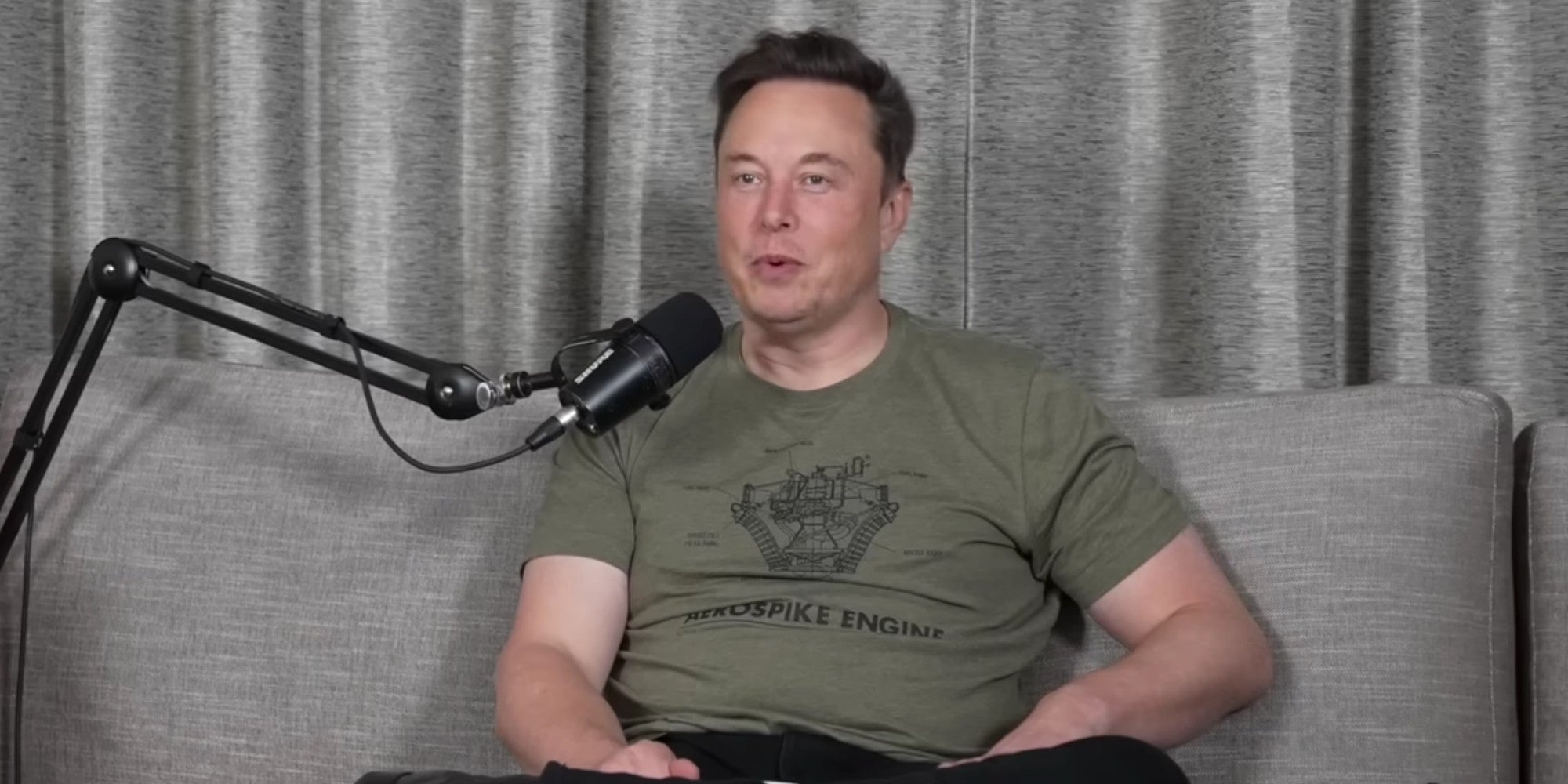 Elon Musk sitting on a couch and speaking into a microphone