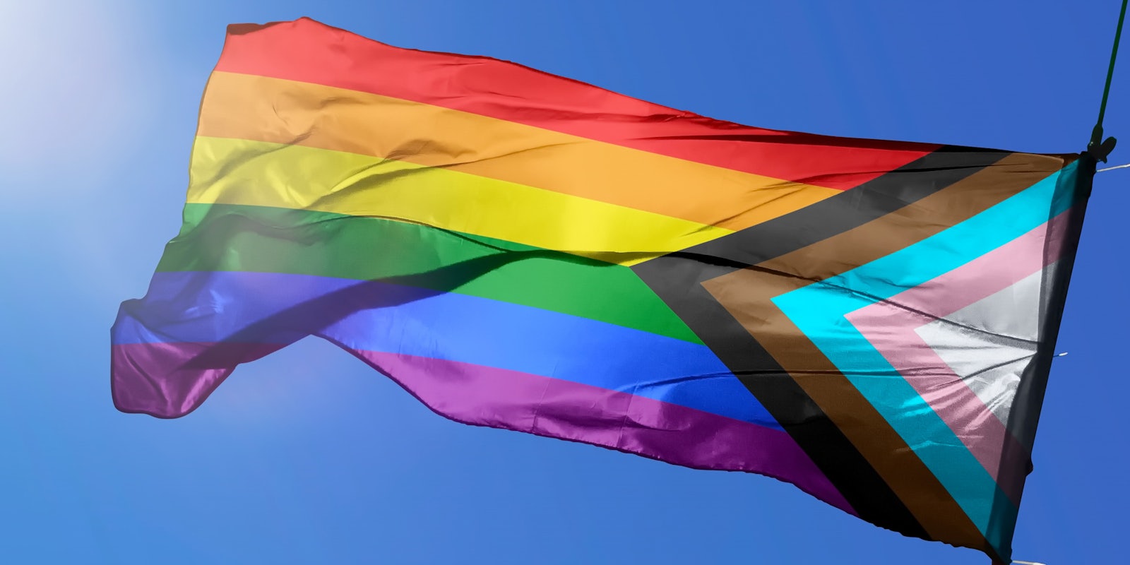 LGBTQ+ pride flag in front of blue sky