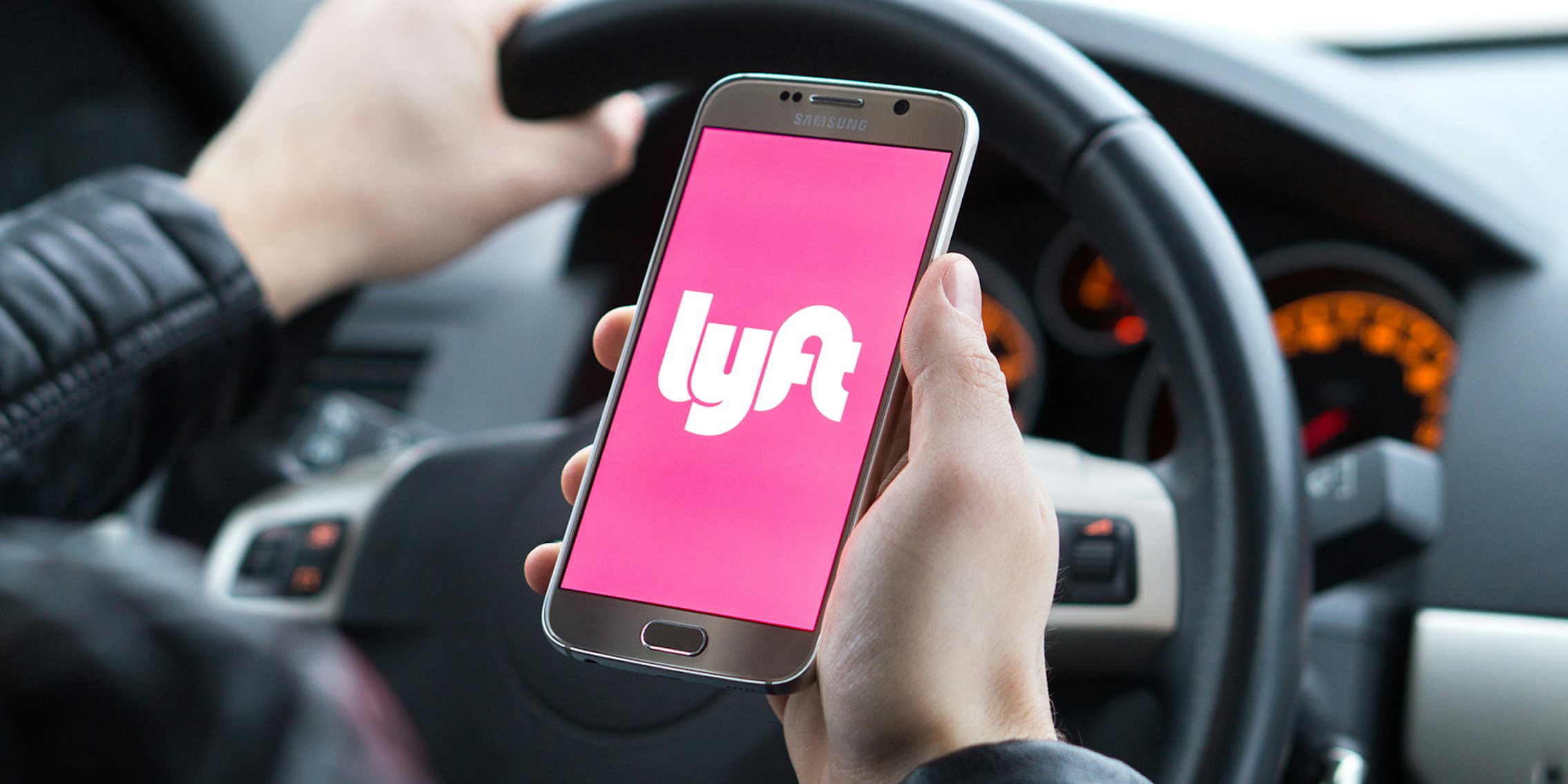 driver holding phone with Lyft app on screen