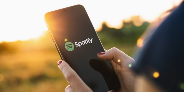 a woman holding a phone with the spotify app open