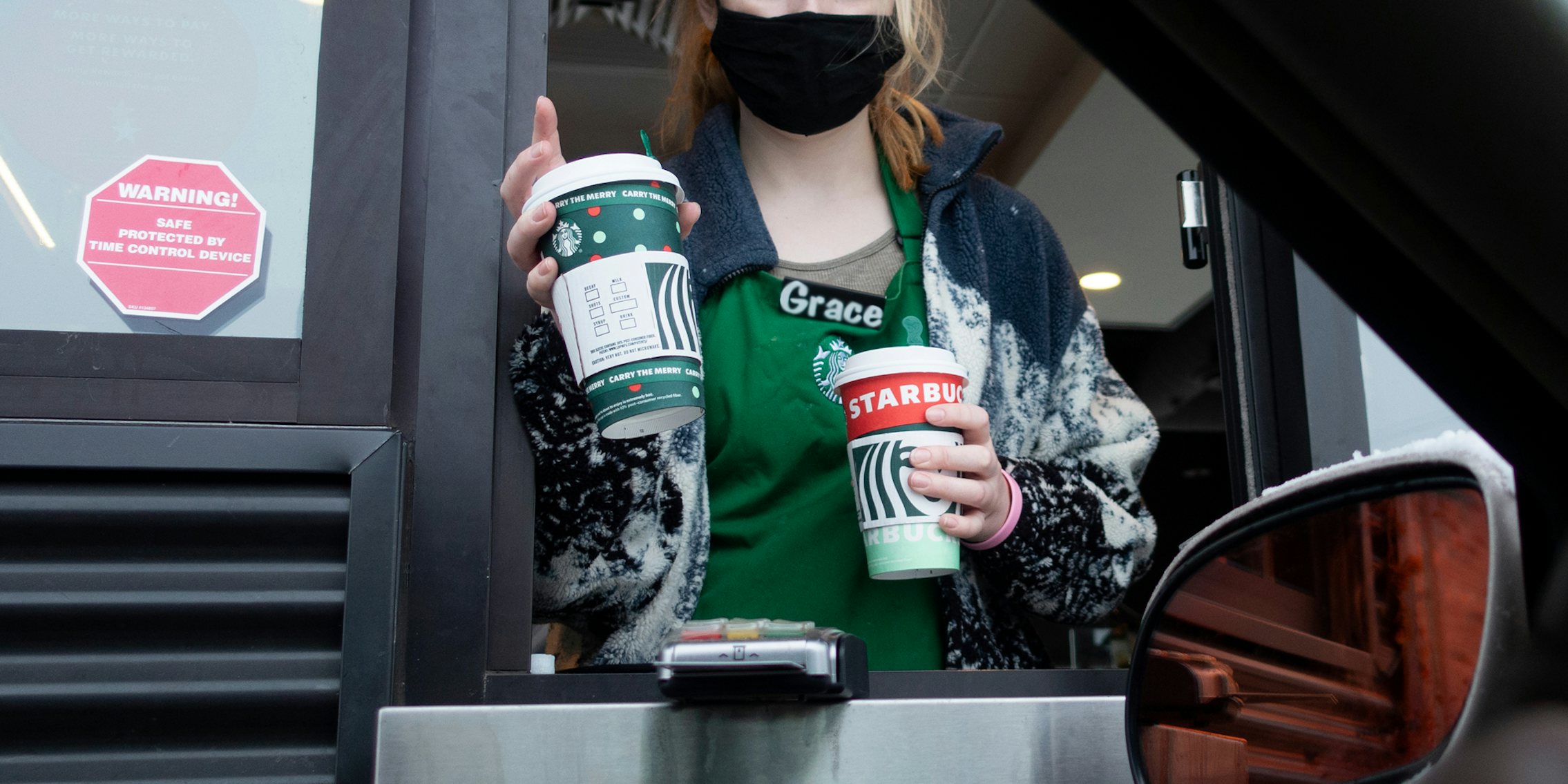 Starbucks barista at drive thru window handing customer drinks