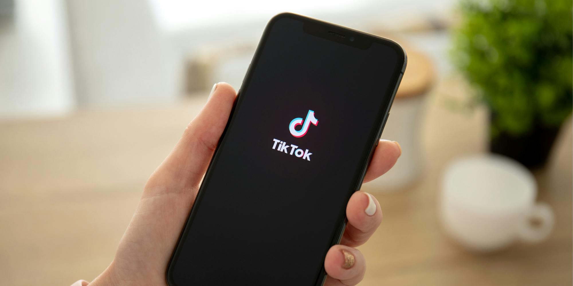 TikTok open on phone in hand in front of blurred background