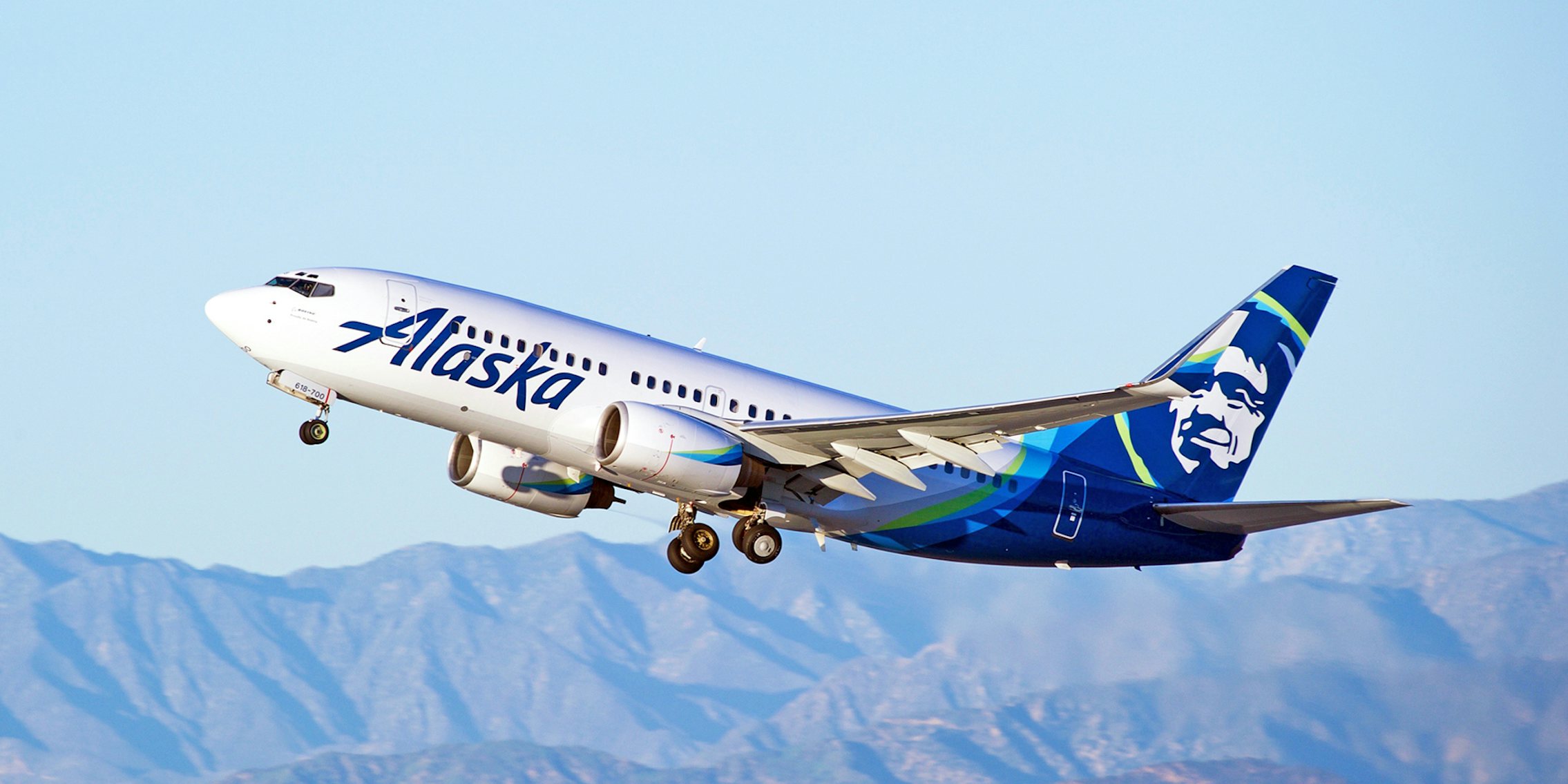 Alaska Airlines Boeing 737 aircraft is airborne with sky and hills in background