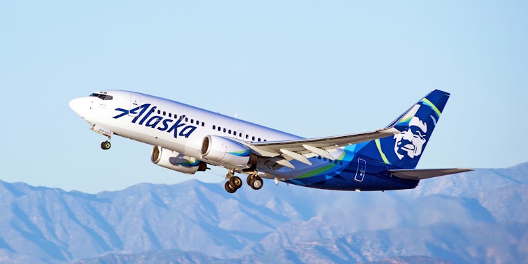 Alaska Airlines Boeing 737 aircraft is airborne with sky and hills in background