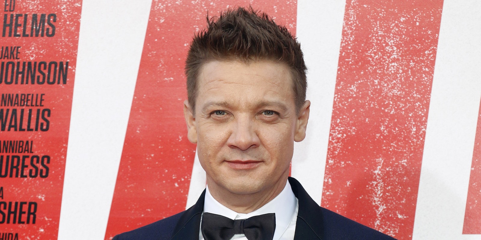 Jeremy Renner in front of red and white background