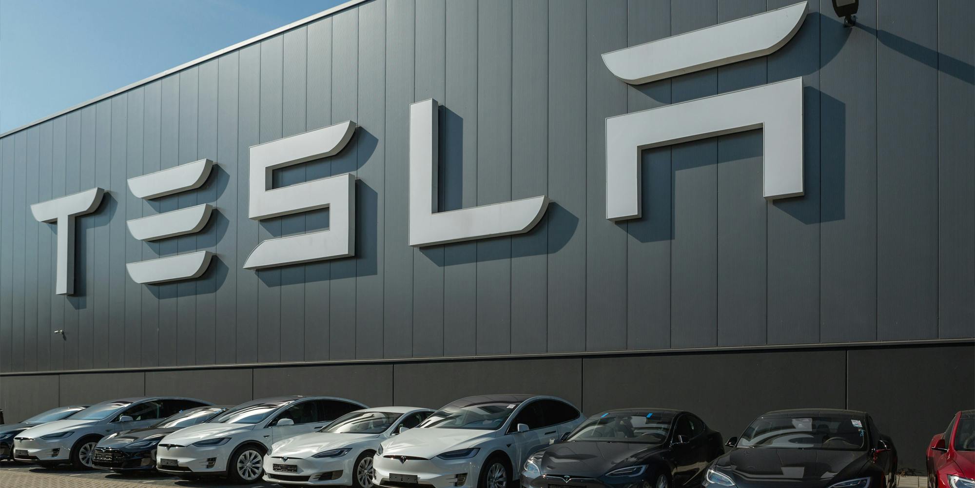 Tesla sign on building with cars parked underneath