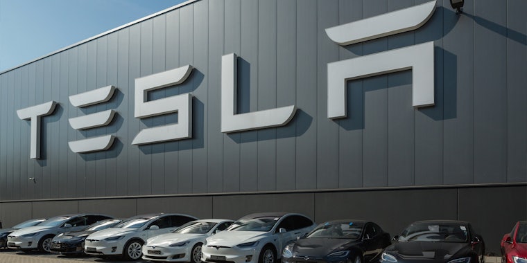 Tesla sign on building with cars parked underneath