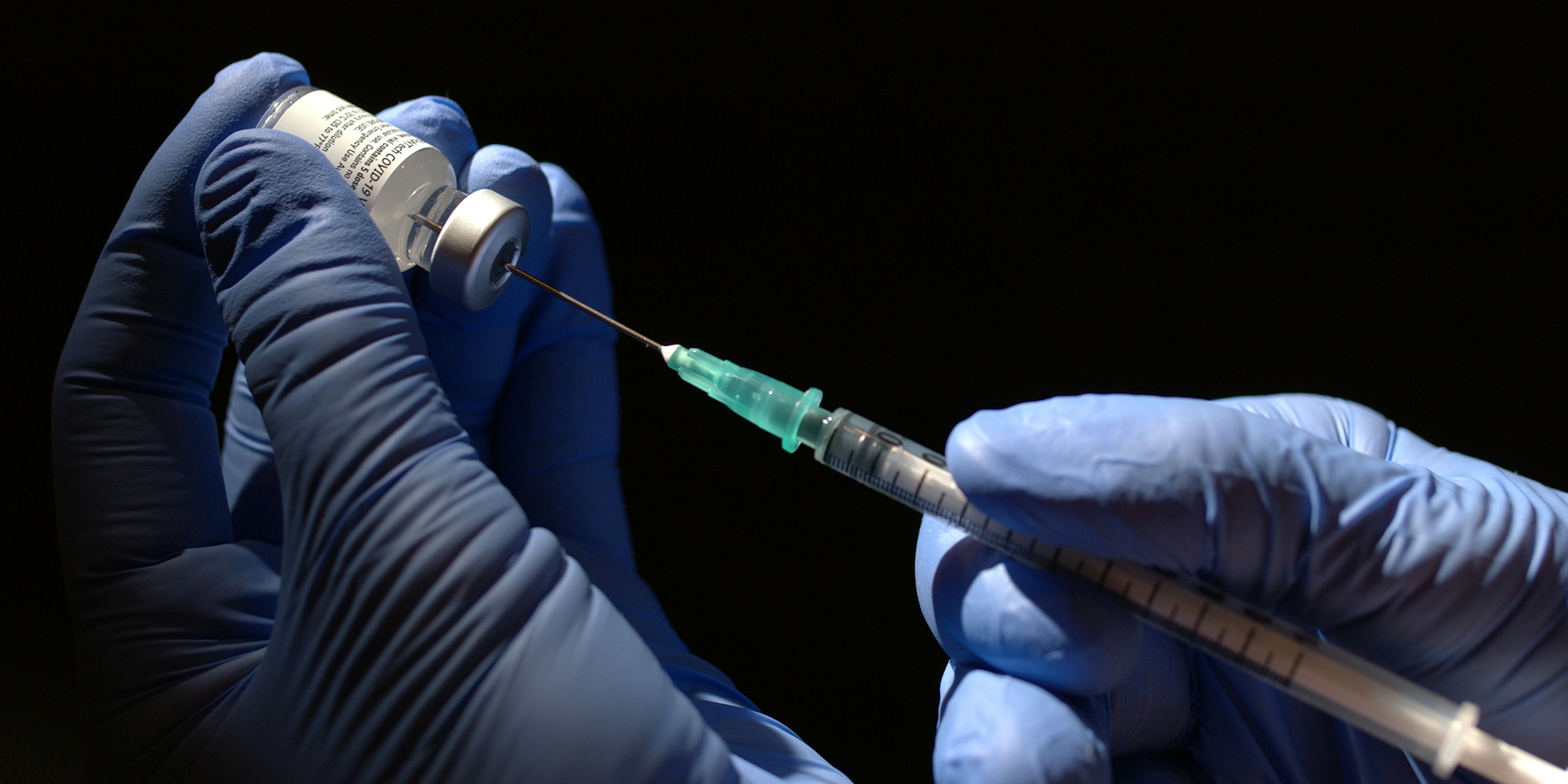 gloved hands holding syringe with covid vaccine