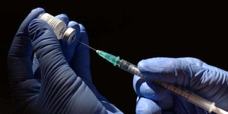 gloved hands holding syringe with covid vaccine