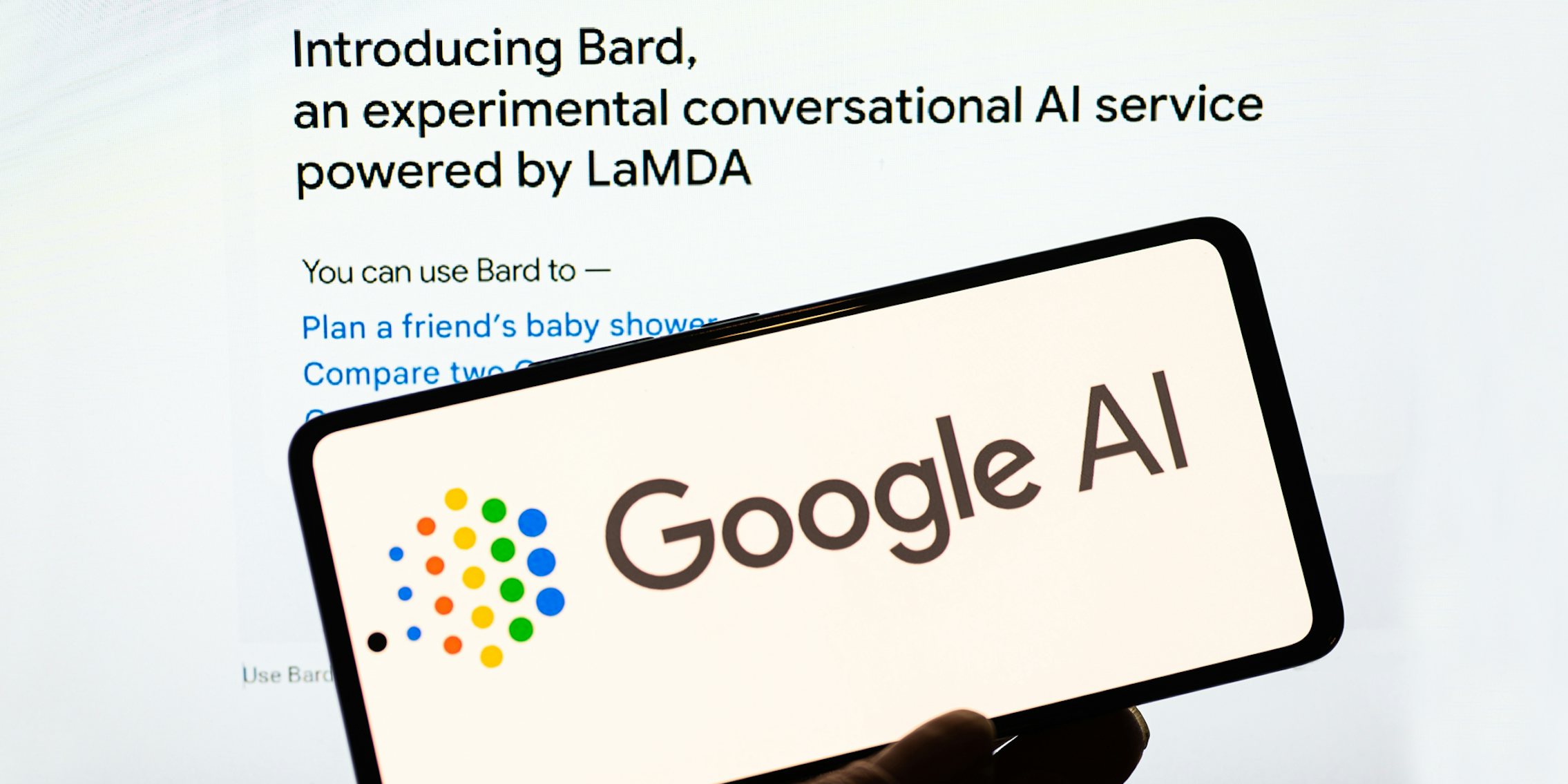 hand holding phone with Google AI on screen in front of Google Bard introduction on website