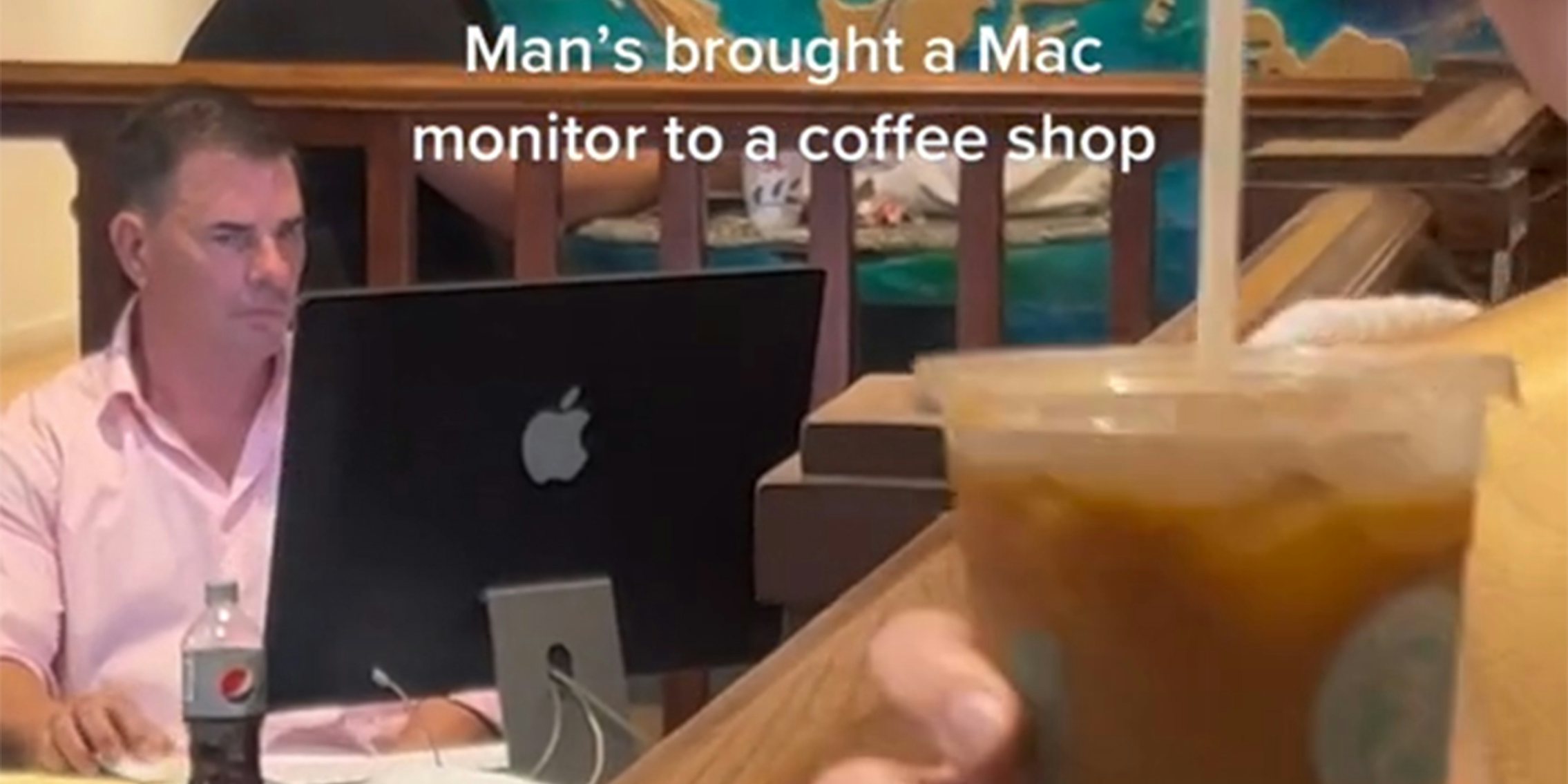 man using full-sized monitor in a coffee shop