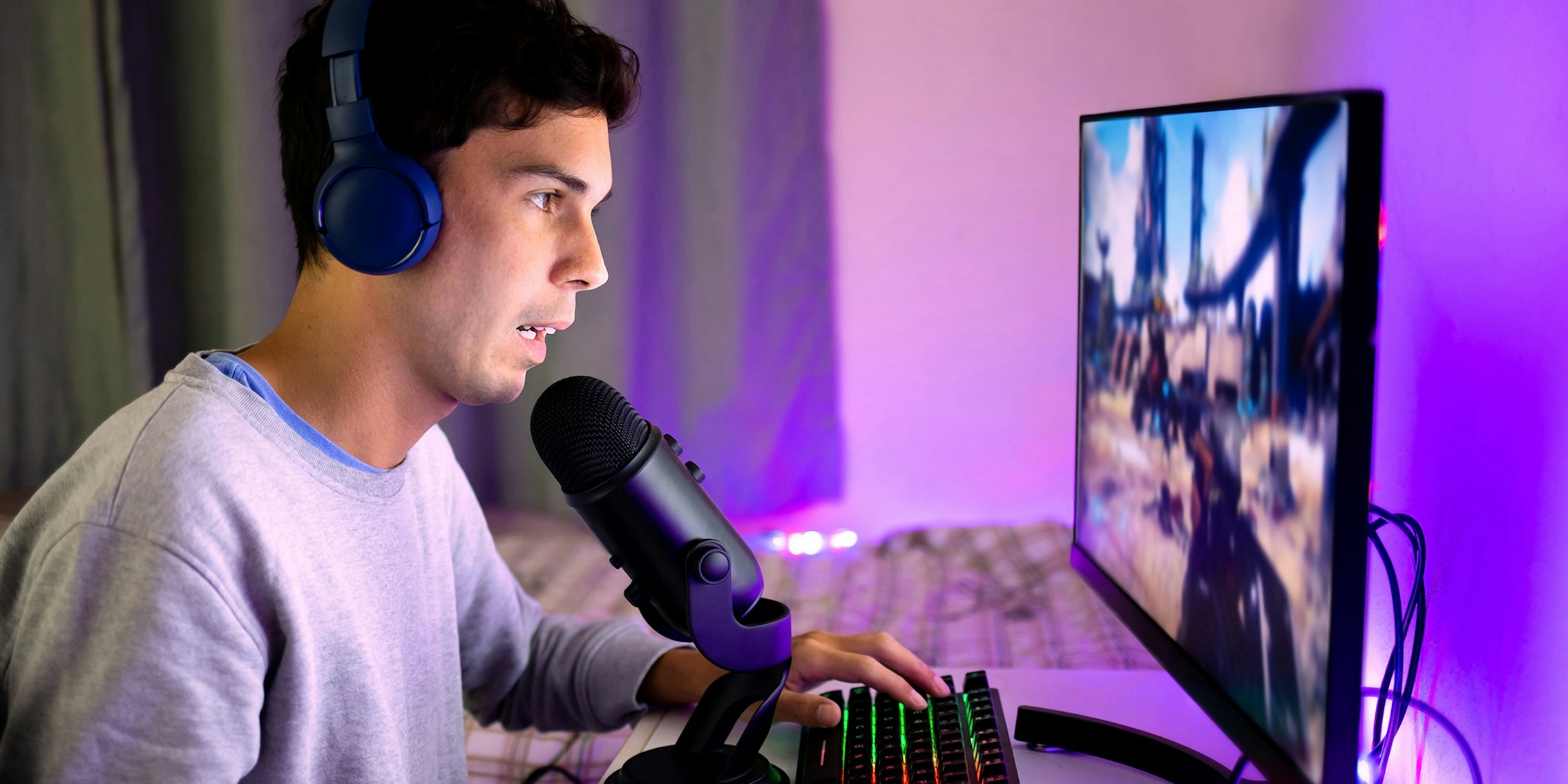 Young man playing video games on the computer in his bedroom and chatting online with other players