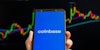 Coinbase on phone in hand in front of chart black background