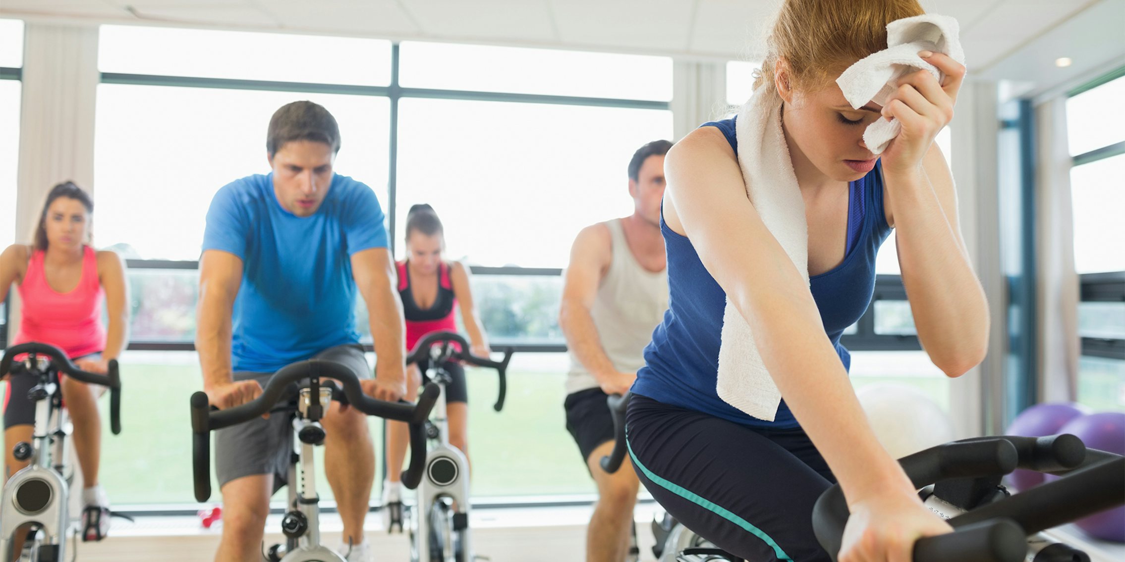 Determined and tired people working out at an exercise bike class in gym