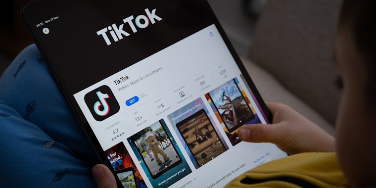 Child holding iPad in lap with TikTok in appstore on screen