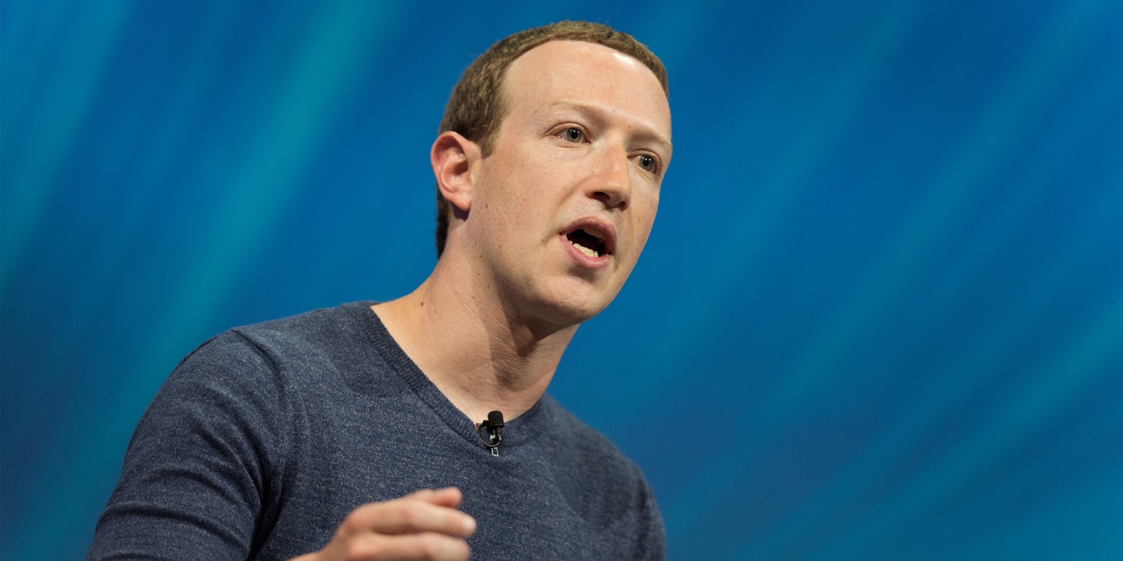 Mark Zuckerberg speaking in front of blue background