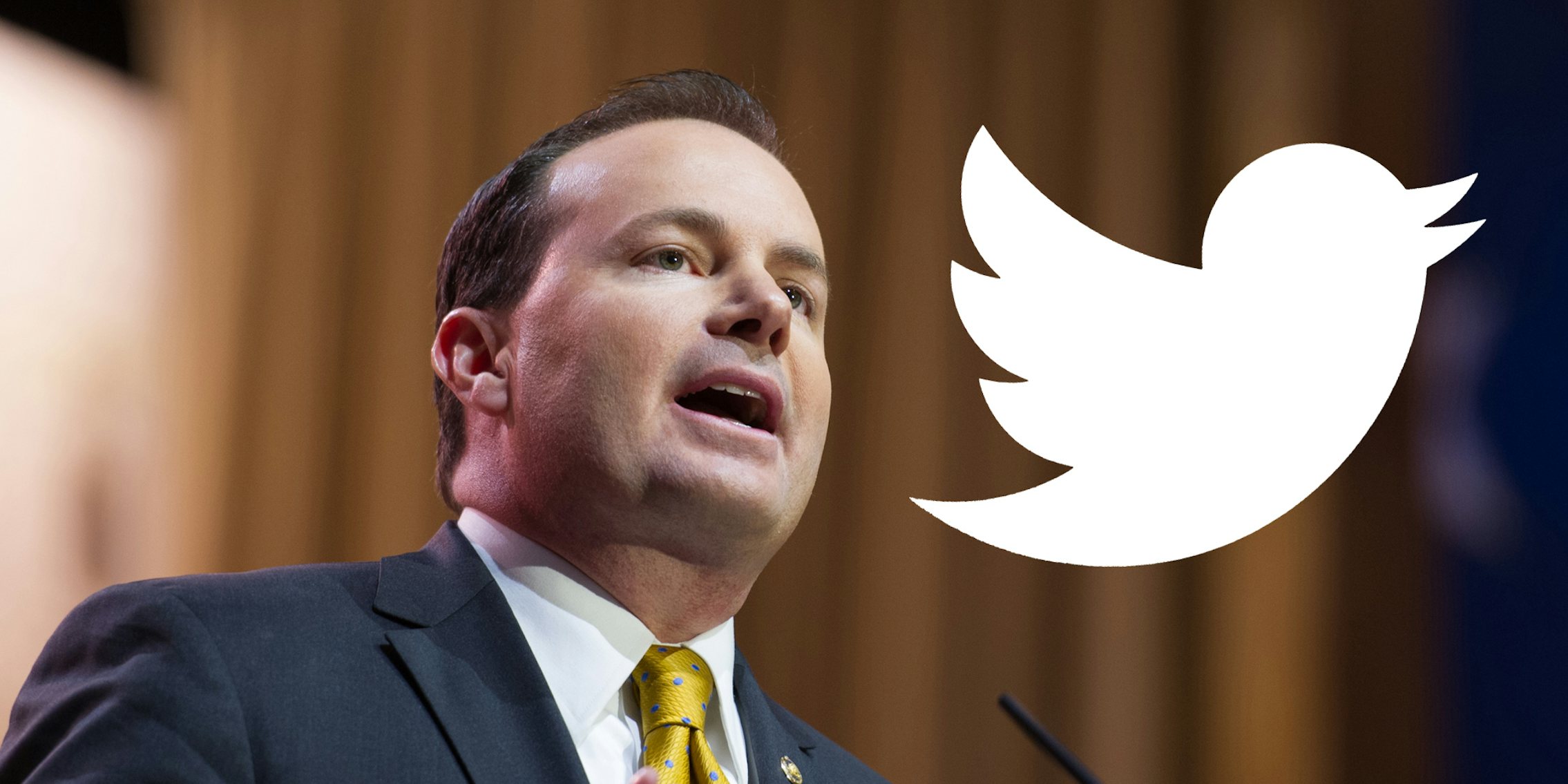 Mike Lee speaking into microphone with white Twitter bird logo to his right