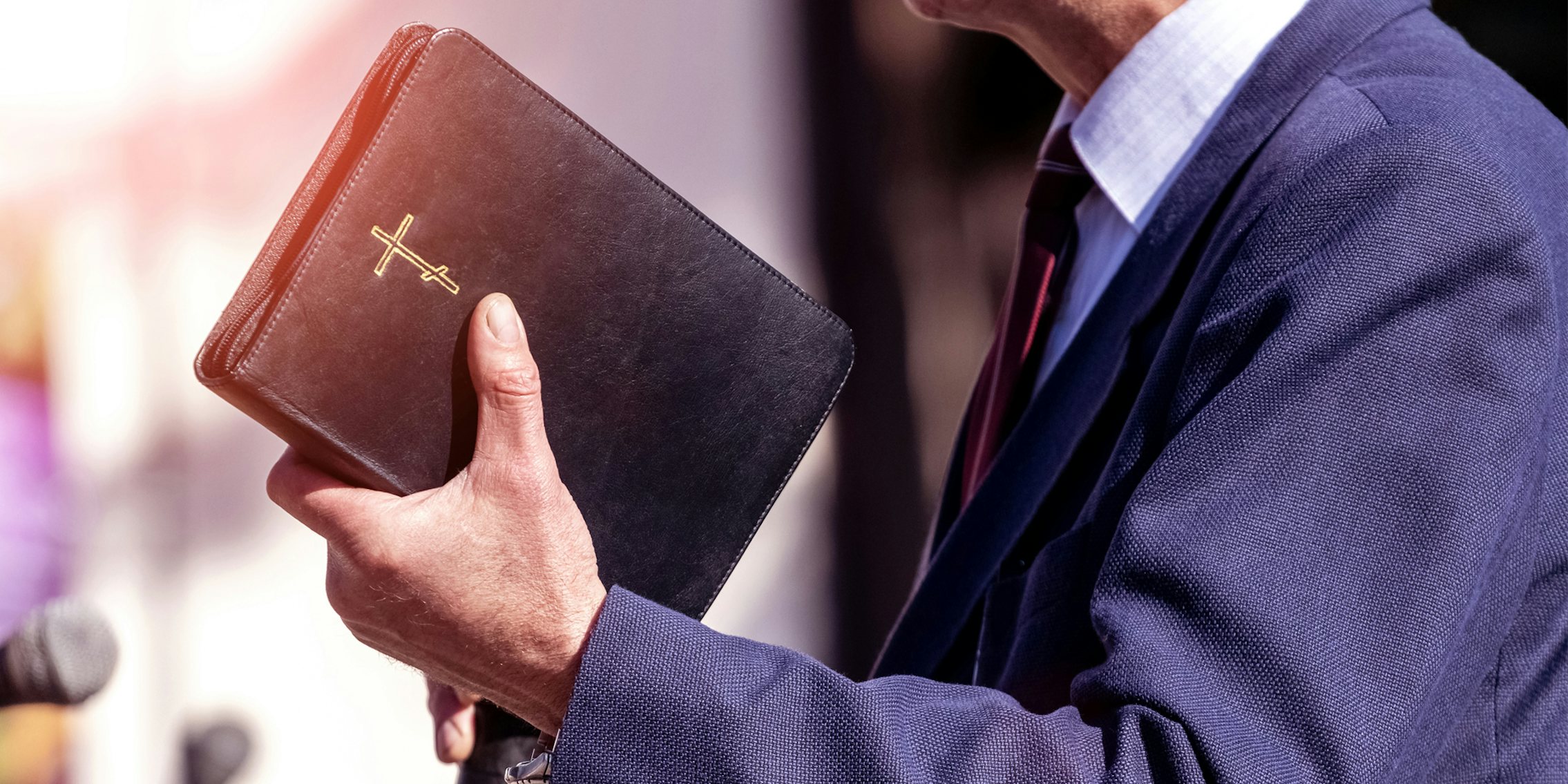 Pastor holding bible speaking into microphone