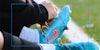 A rainbow lace is seen being tied on a football boot next to a cone during Stonewall's rainbow laces 