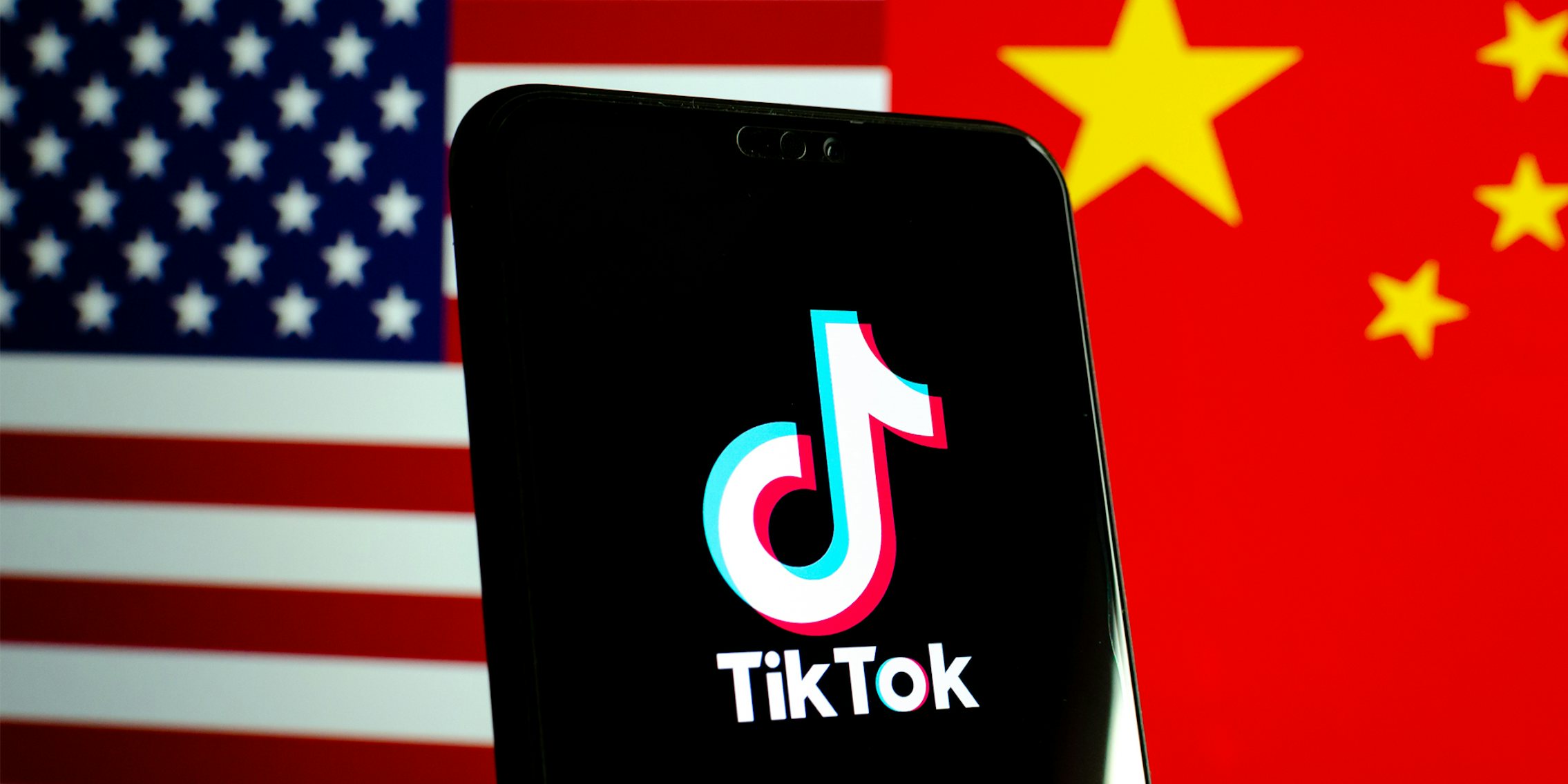 TikTok on phone screen in front of half split US flag and China flag background