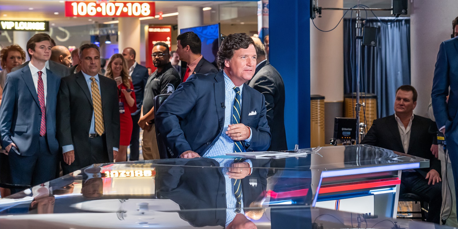 Tucker Carlson sitting in chair at table at Fox news station