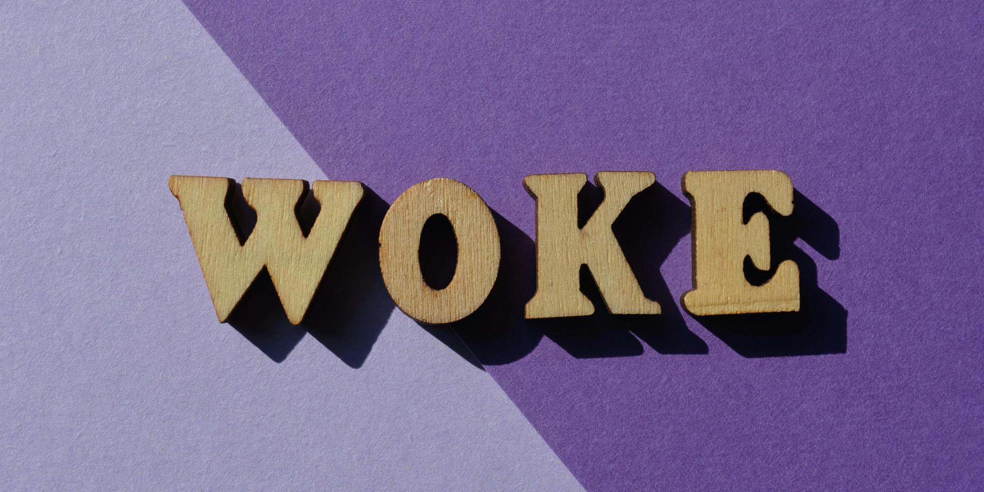 WOKE wooden letters on diagonal split light to dark horizontal background