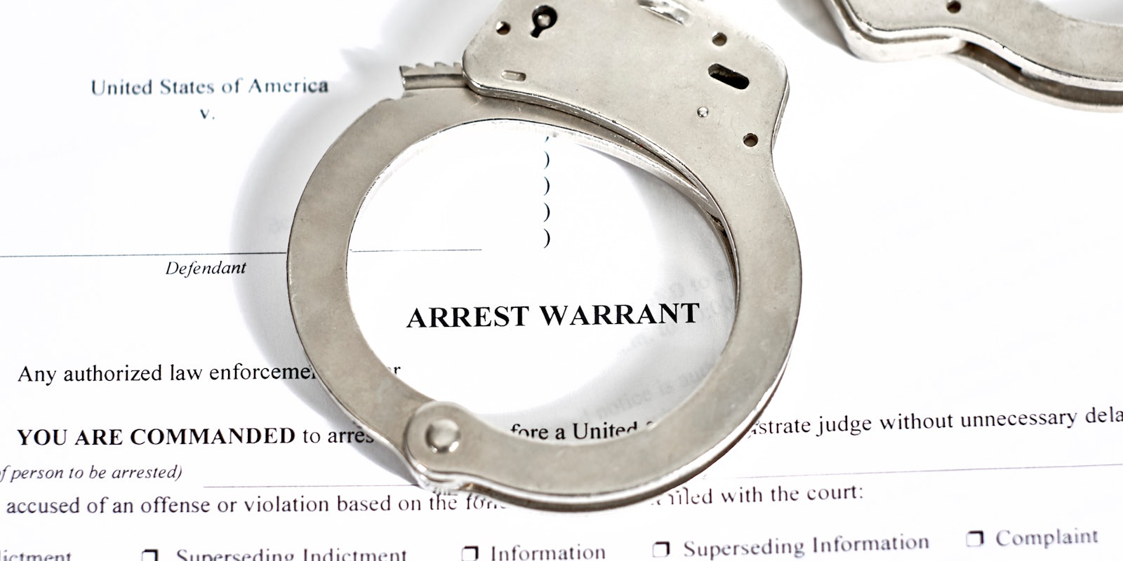 Arrest Warrant court papers with handcuffs on top