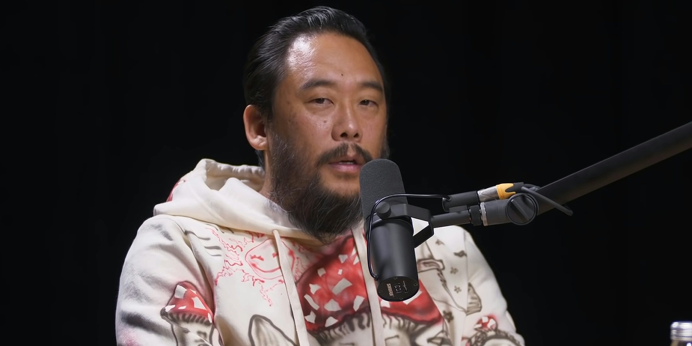 David Choe speaking into microphone in front of black background