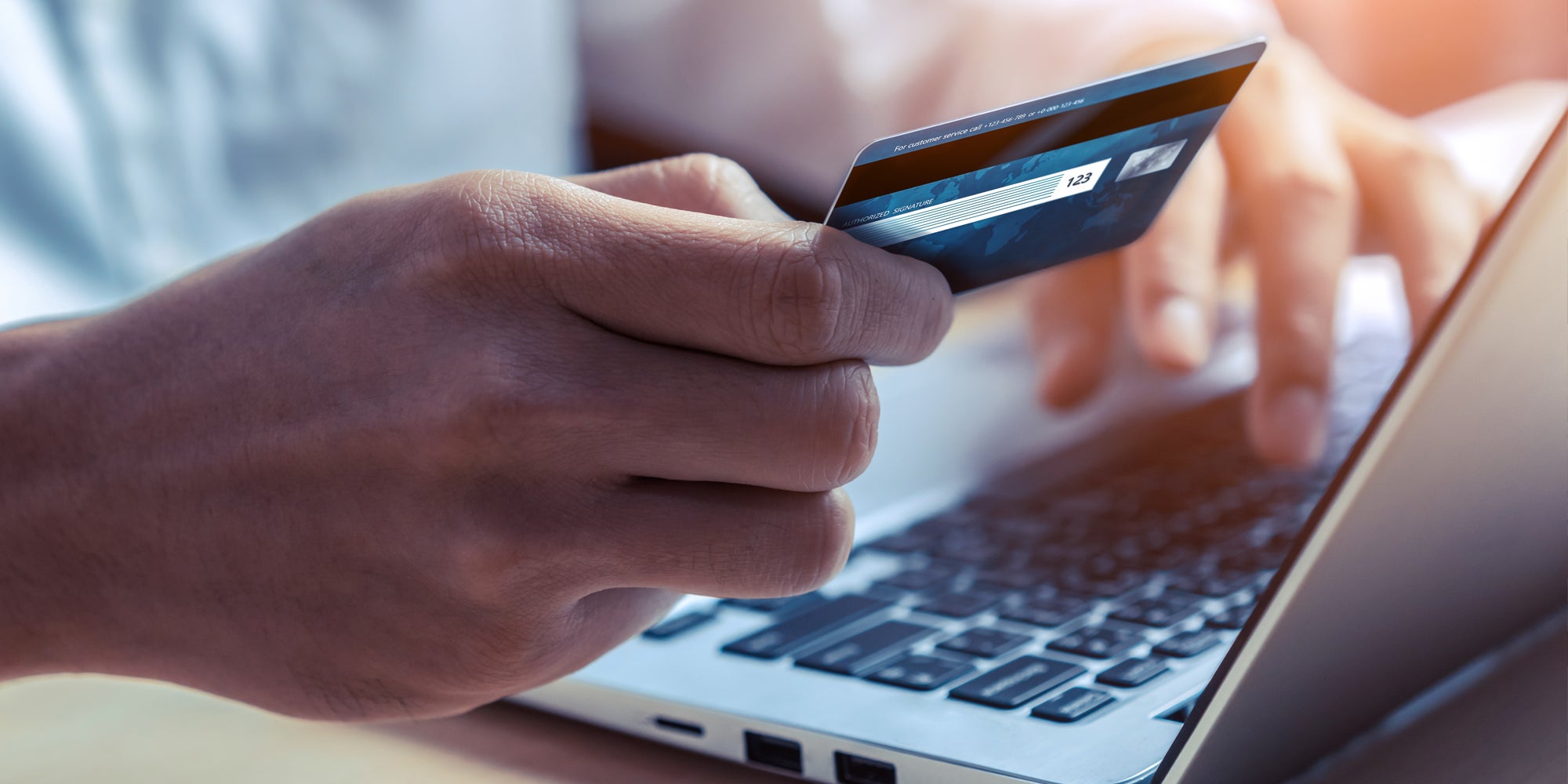person holding credit card while typing on laptop