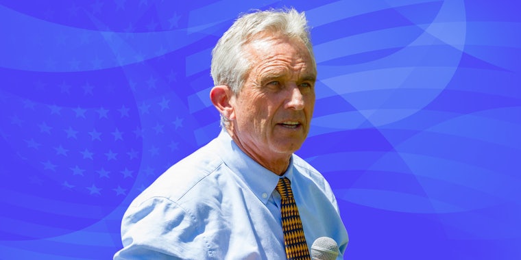 Robert F Kennedy Jr. speaking into microphone in front of blue American flag background