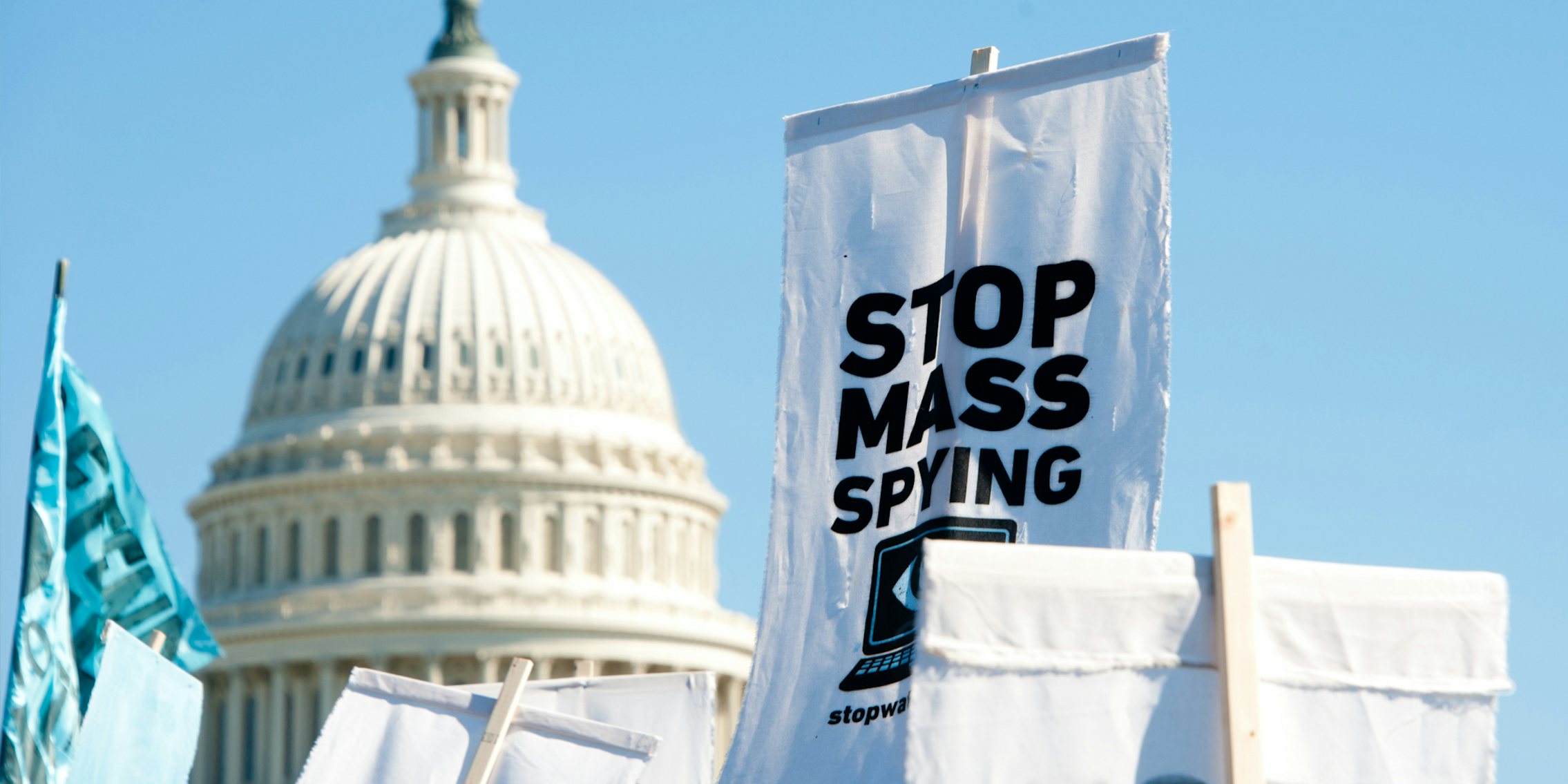 US Capitol building with STOP MASS SPYING protest signs being held up