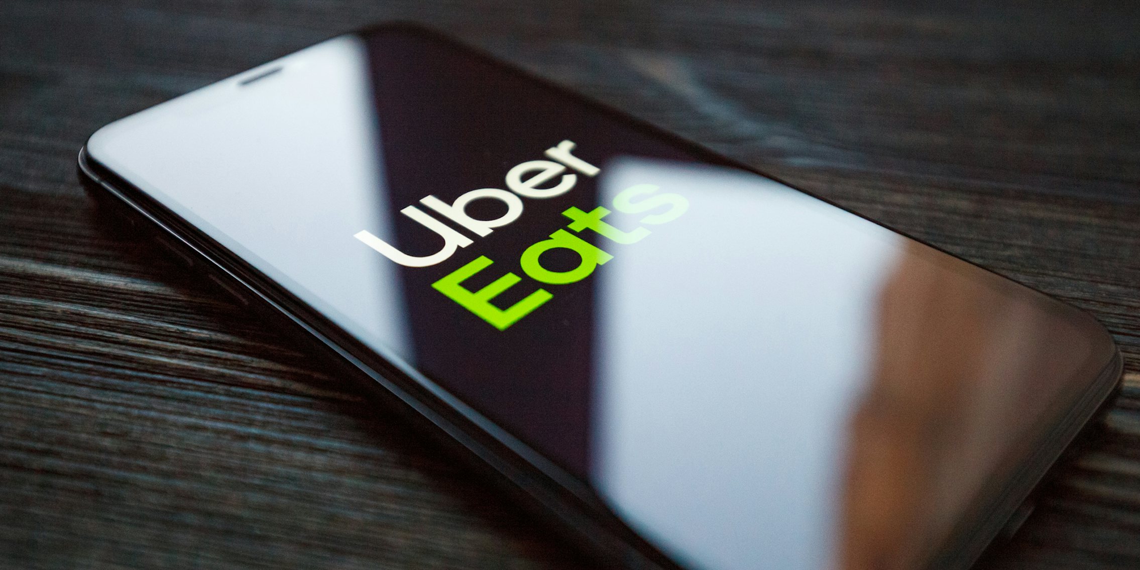 Uber Eats on phone screen on dark wood surface