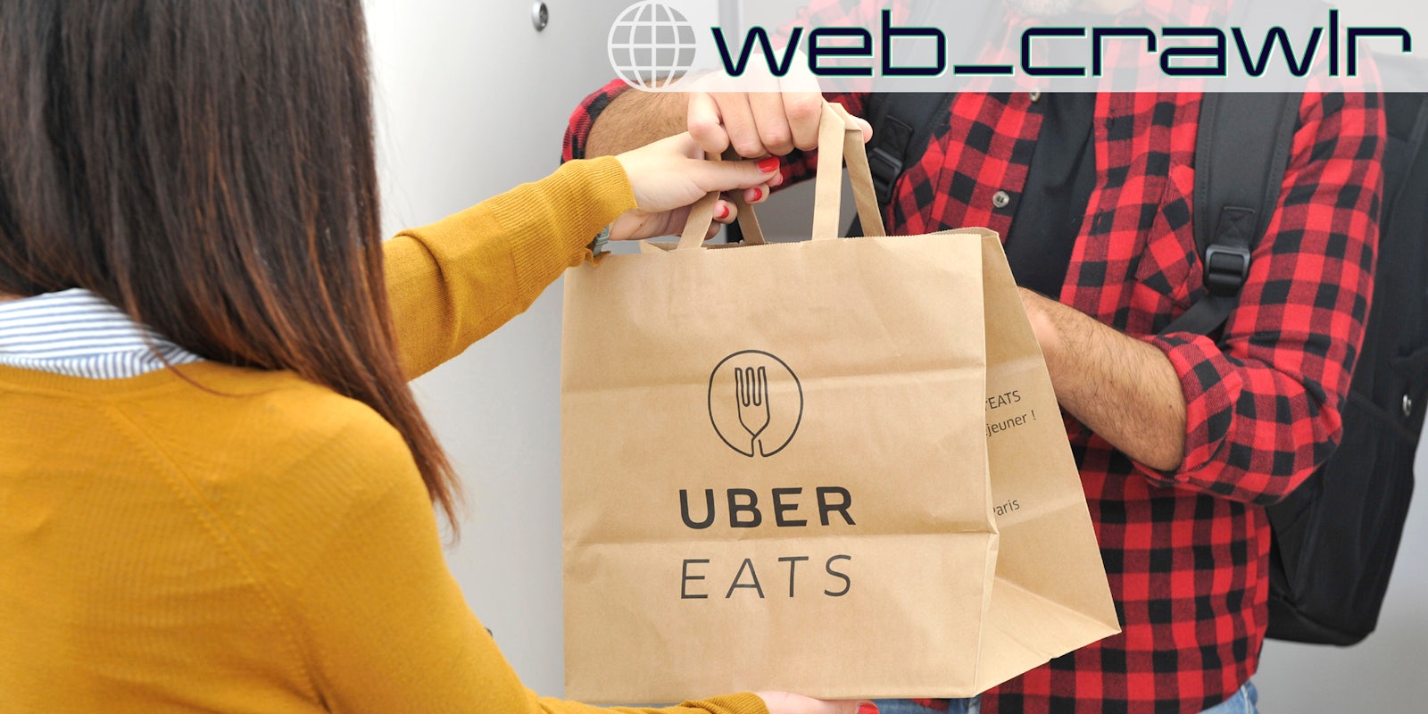 A person handing someone a bag with Uber Eats written on it. The Daily Dot newsletter web_crawlr logo is in the top right corner.