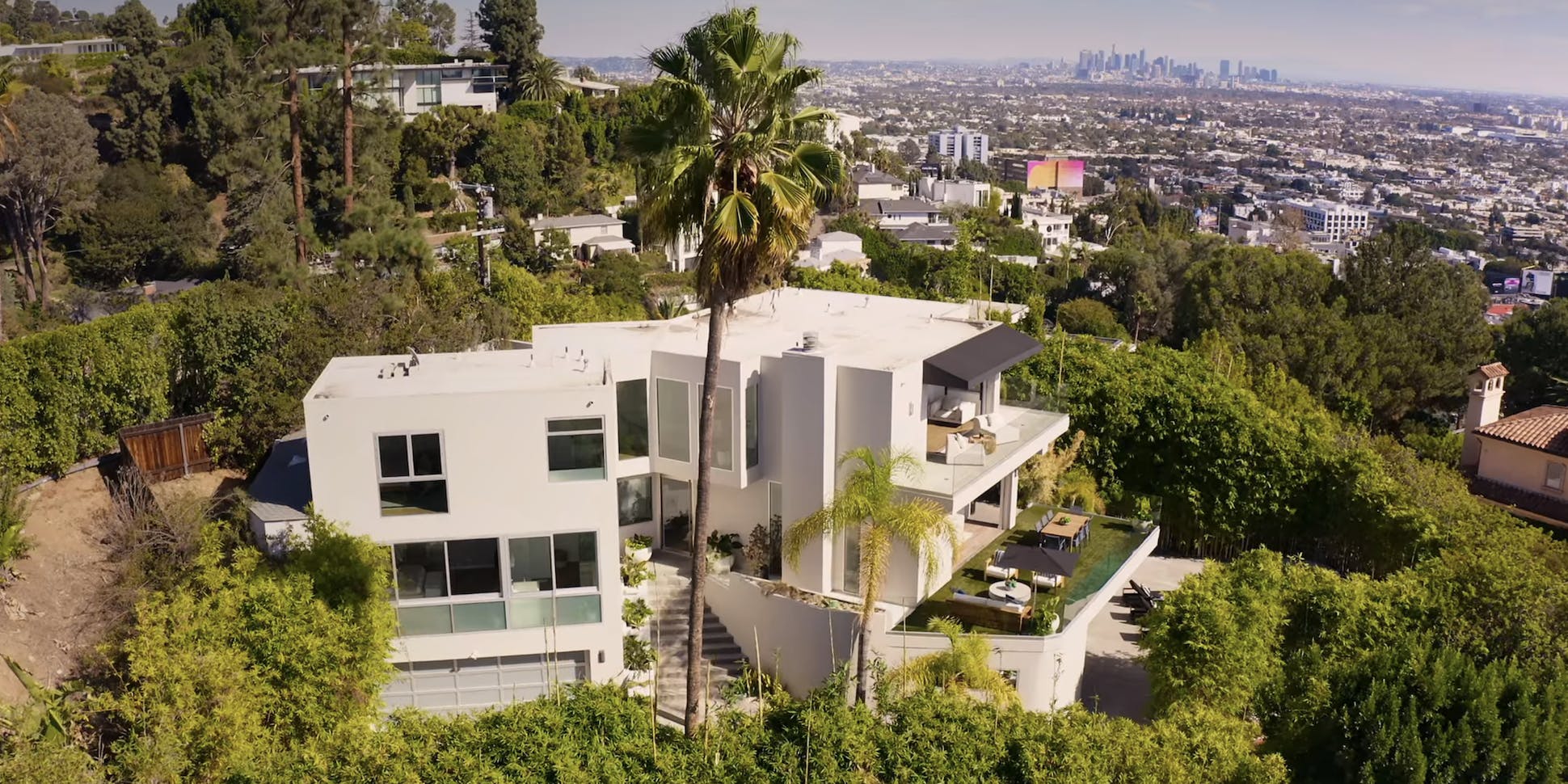 a multi-level white house with a tall palm tree on a hill in Los Angeles, the former home of Harry Styles