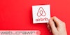 A hand holding an Airbnb card. The Daily Dot newsletter web_crawlr logo is in the bottom left corner.